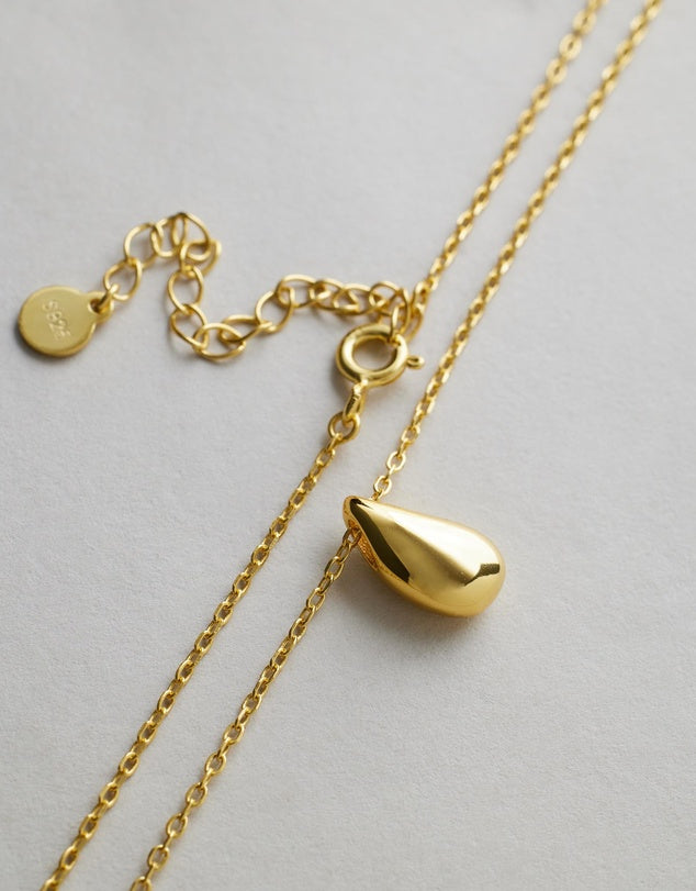 Gold Capri Teardrop Necklace with a pendant on a light gray background