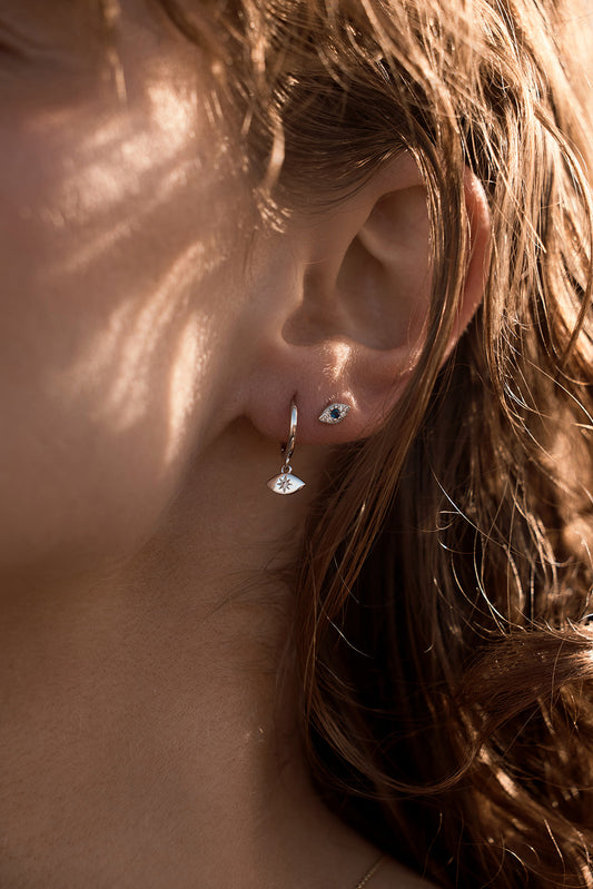 Evil Eye Studs - Silver earrings close up on a womens ear