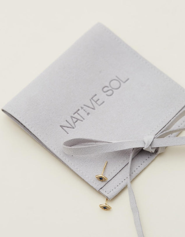 Evil Eye Studs - Gold laid out on grey jewellery pouch