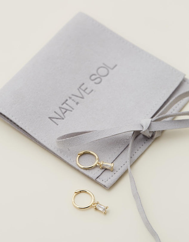 Rita Huggies - Clear & Gold laid out on grey jewellery pouch