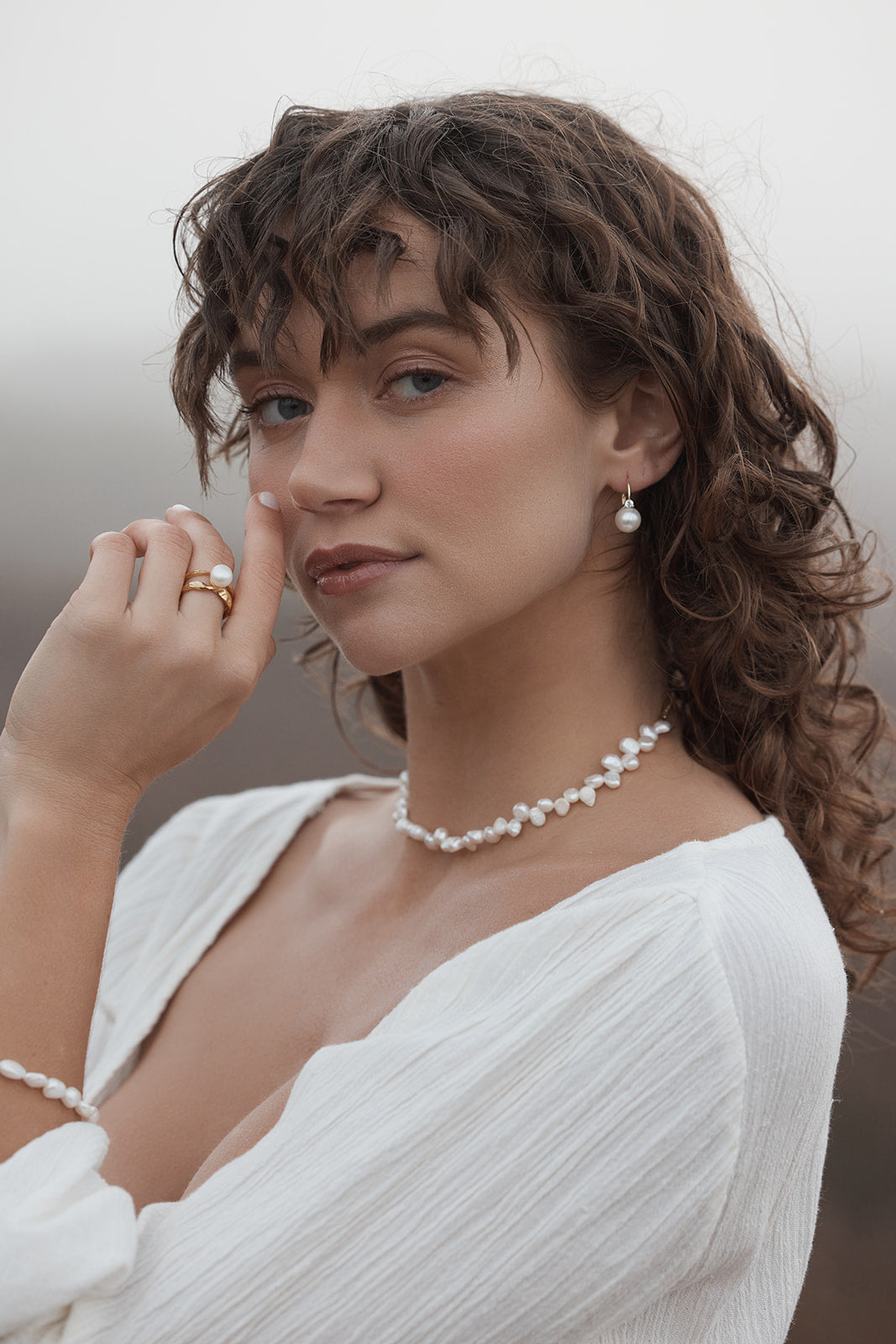 Woman wearing Cecilia Pearl Choker and earrings with a blurred background
