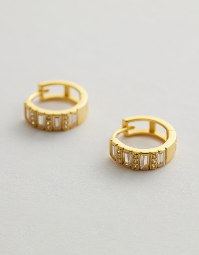 Elysia Diamond Huggie Earrings with embedded stones on a light gray background