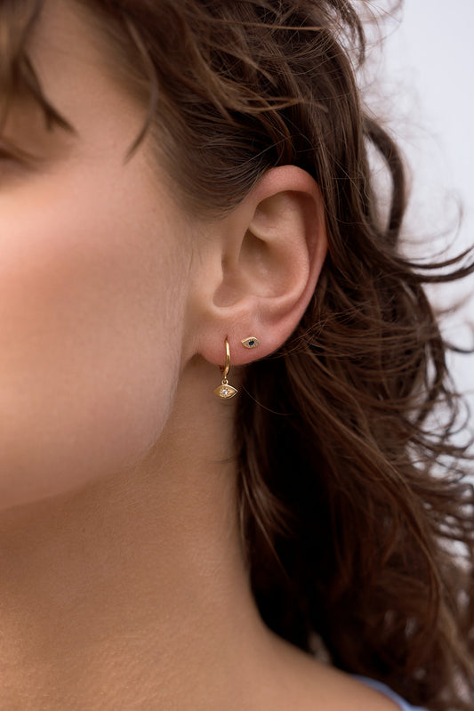 Close-up of an ear wearing Evil Eye Huggies - Gold earring