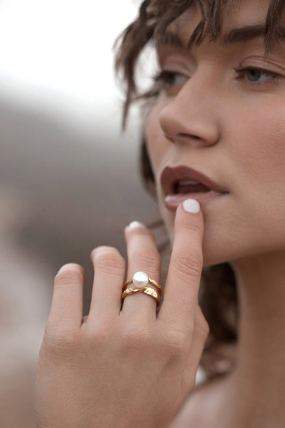 Close-up of a woman's hand with a Isla Pearl Ring on her finger, blurred background