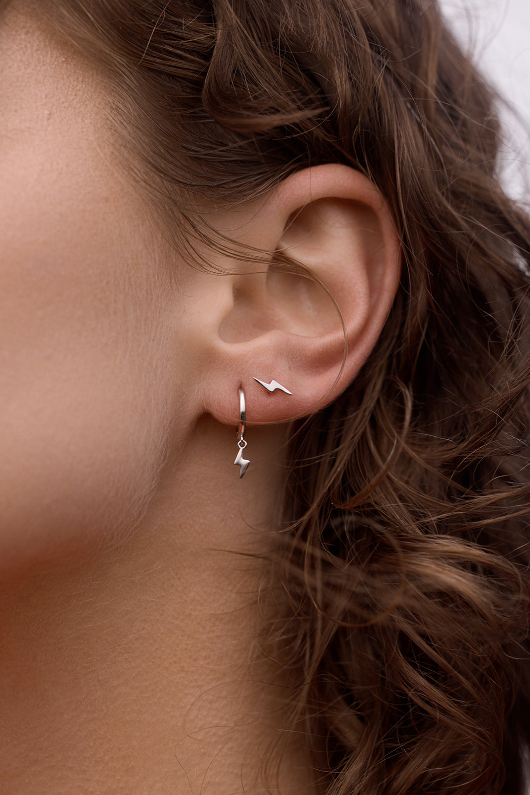Close-up of Lightning Bolt Huggies - Silver on a womens ear