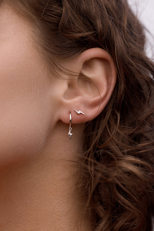 Close-up of Lightning Bolt Huggies - Silver on a womens ear