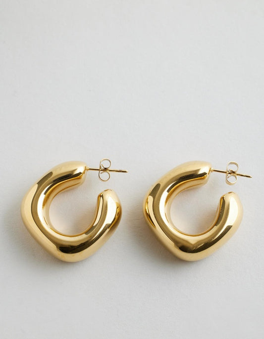 Sally Chunky Hoop Earrings - Gold on a white background.
