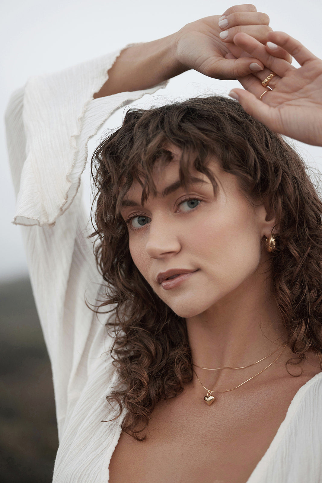 Woman with curly hair wearing gold Snake Chain jewelry against a neutral background