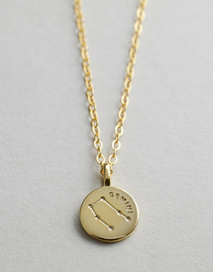 Gold Starsign_Necklace with a round pendant featuring the Gemini zodiac sign on a light gray background