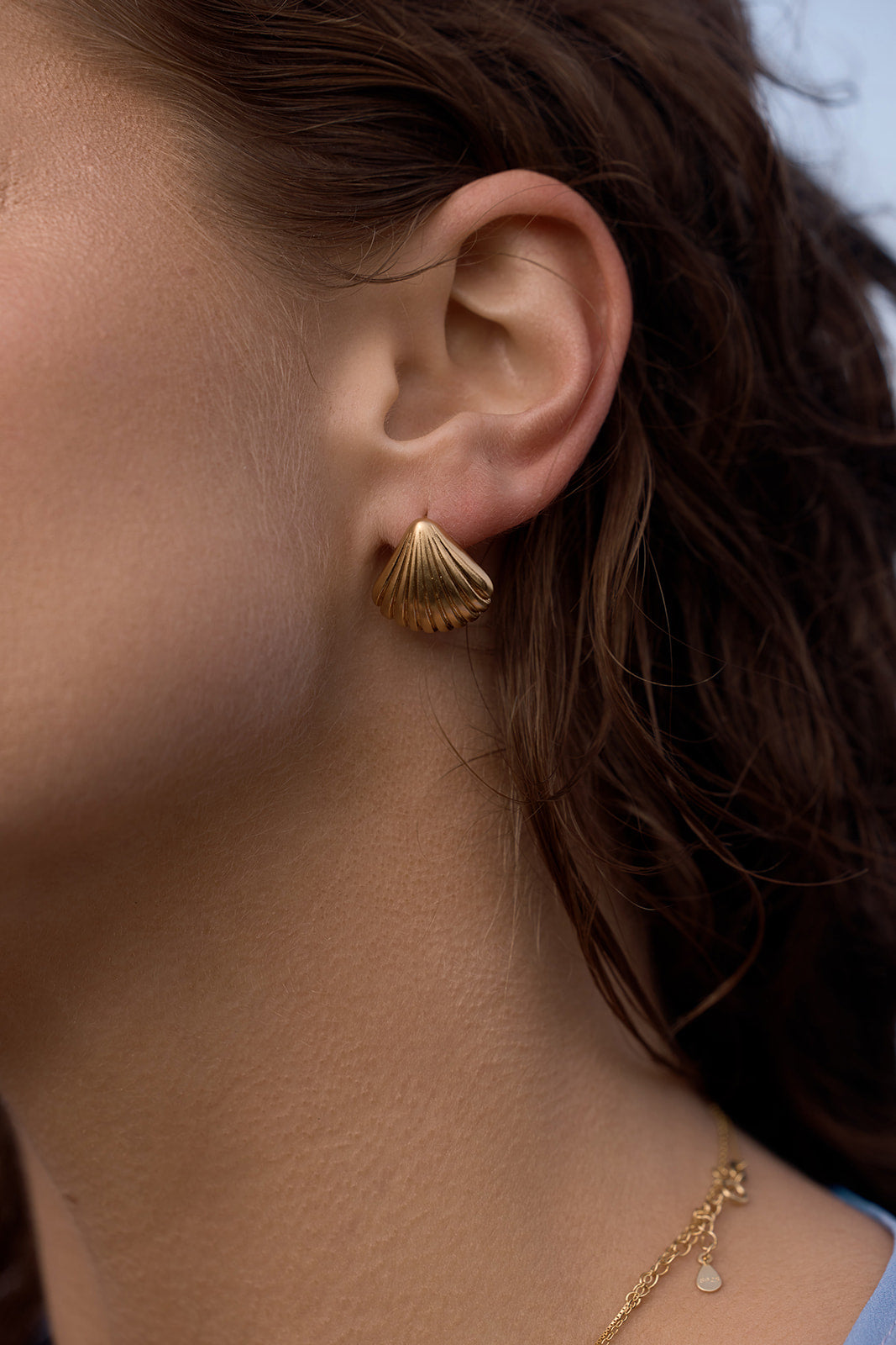 Tanah Shell Earrings - Gold close up on a women's ear