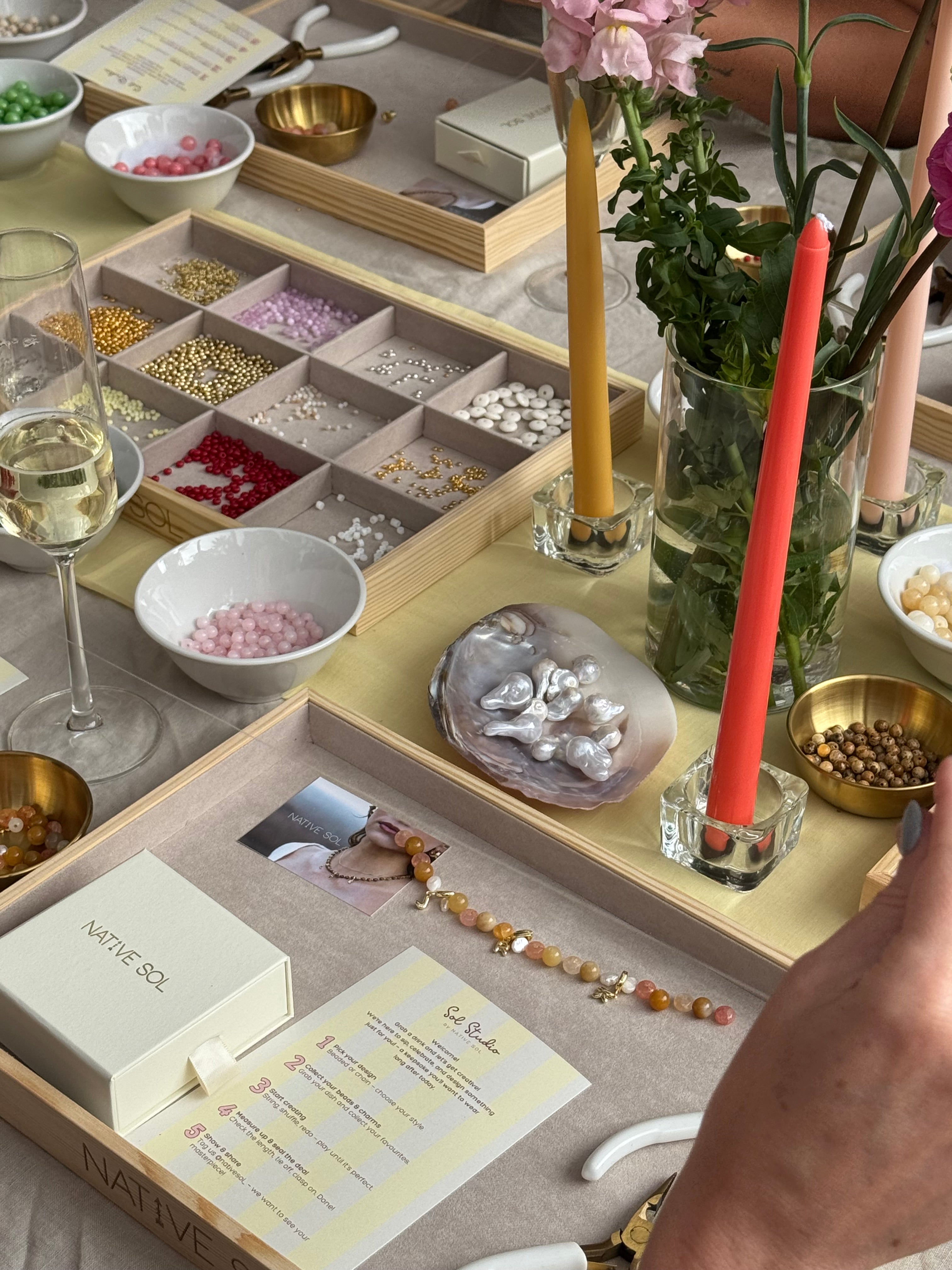 Close-up of a table with decorative items including candles, flowers, and jewelry, beads for jewellery making workshop event