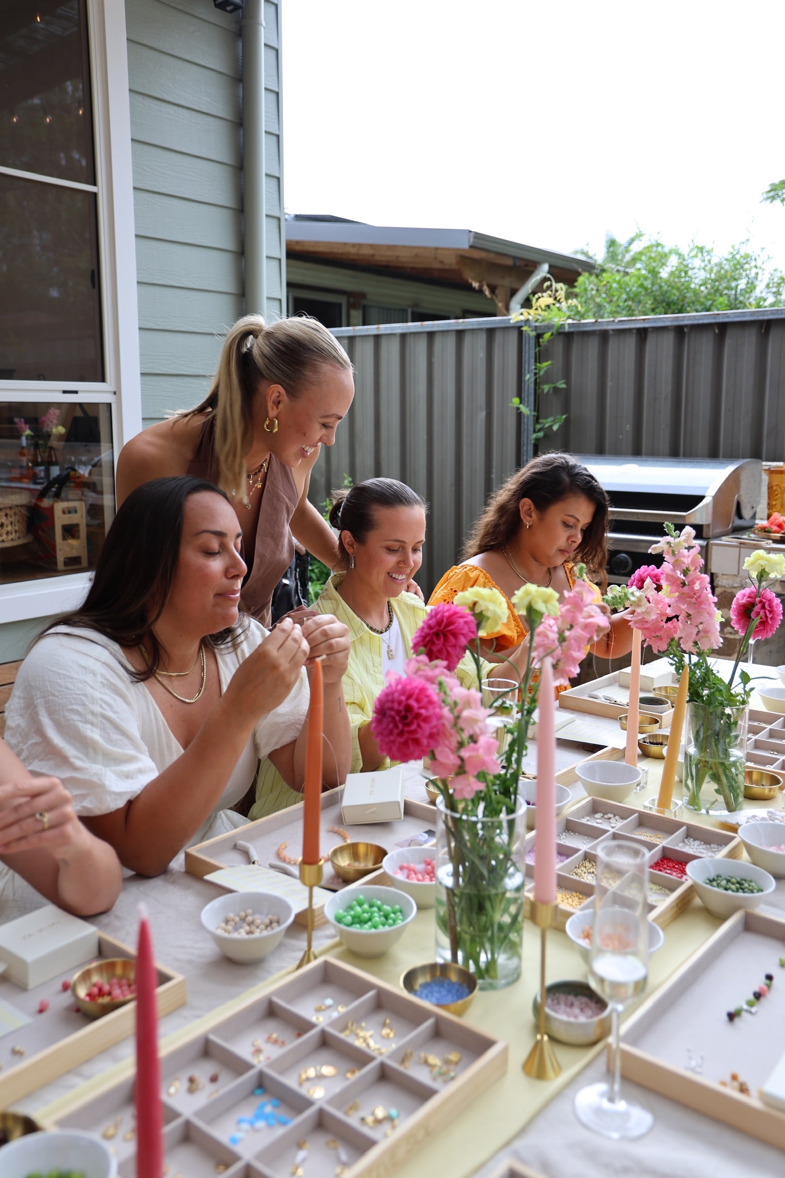 Group of women at an outdoor table with jewelry-making workshop, hens party, girls activity. 