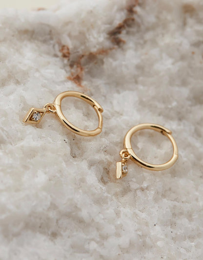 Ava Diamond Huggies - Gold earrings on beige stone