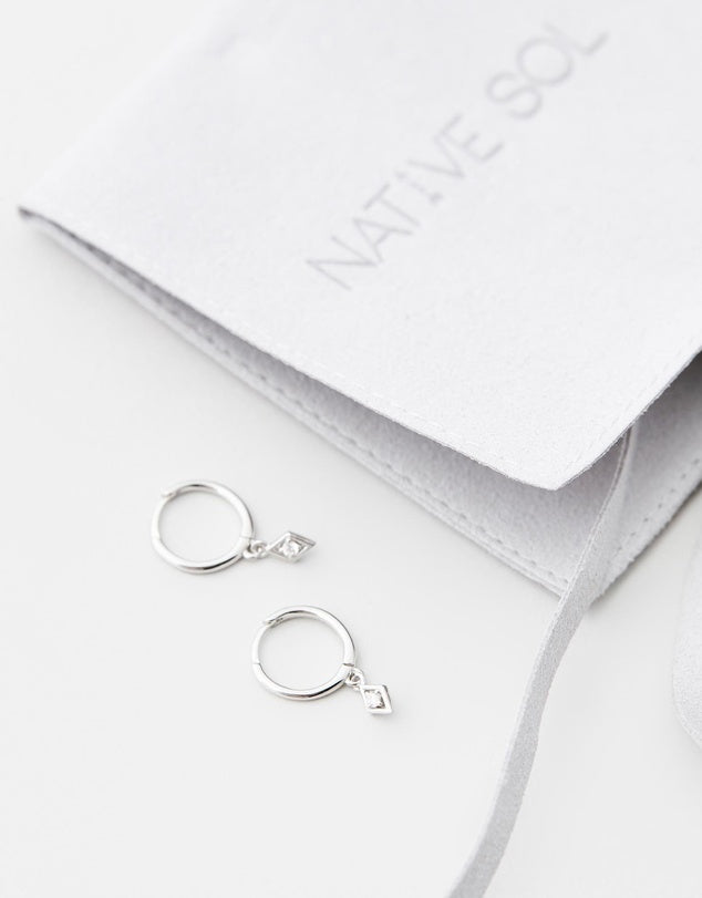 Ava Diamond Huggies - Silver flat lay on white background with jewellery pouch