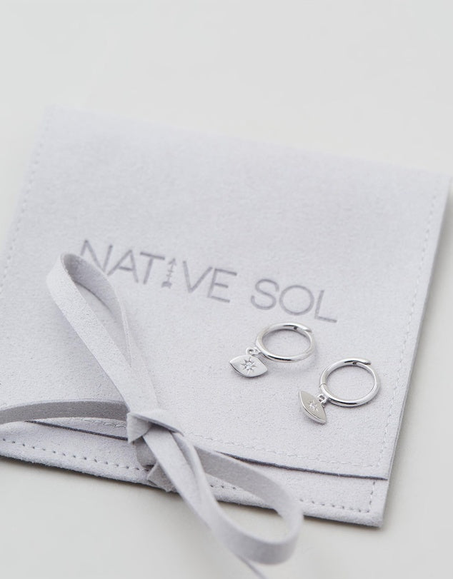 Evil Eye Huggies - Silver close up earrings laid out on earring pouch