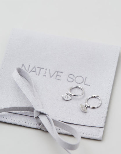 Evil Eye Huggies - Silver close up earrings laid out on earring pouch