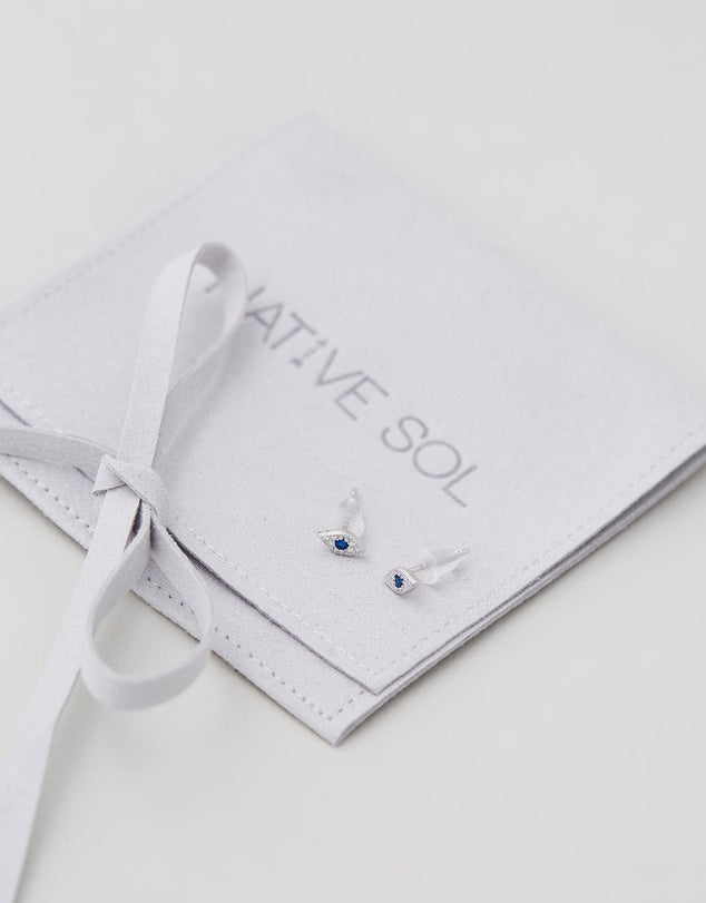 Evil Eye Studs - Silver laid out on grey branded jewellery pouch