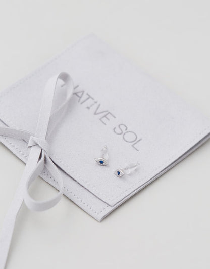 Evil Eye Studs - Silver laid out on grey branded jewellery pouch