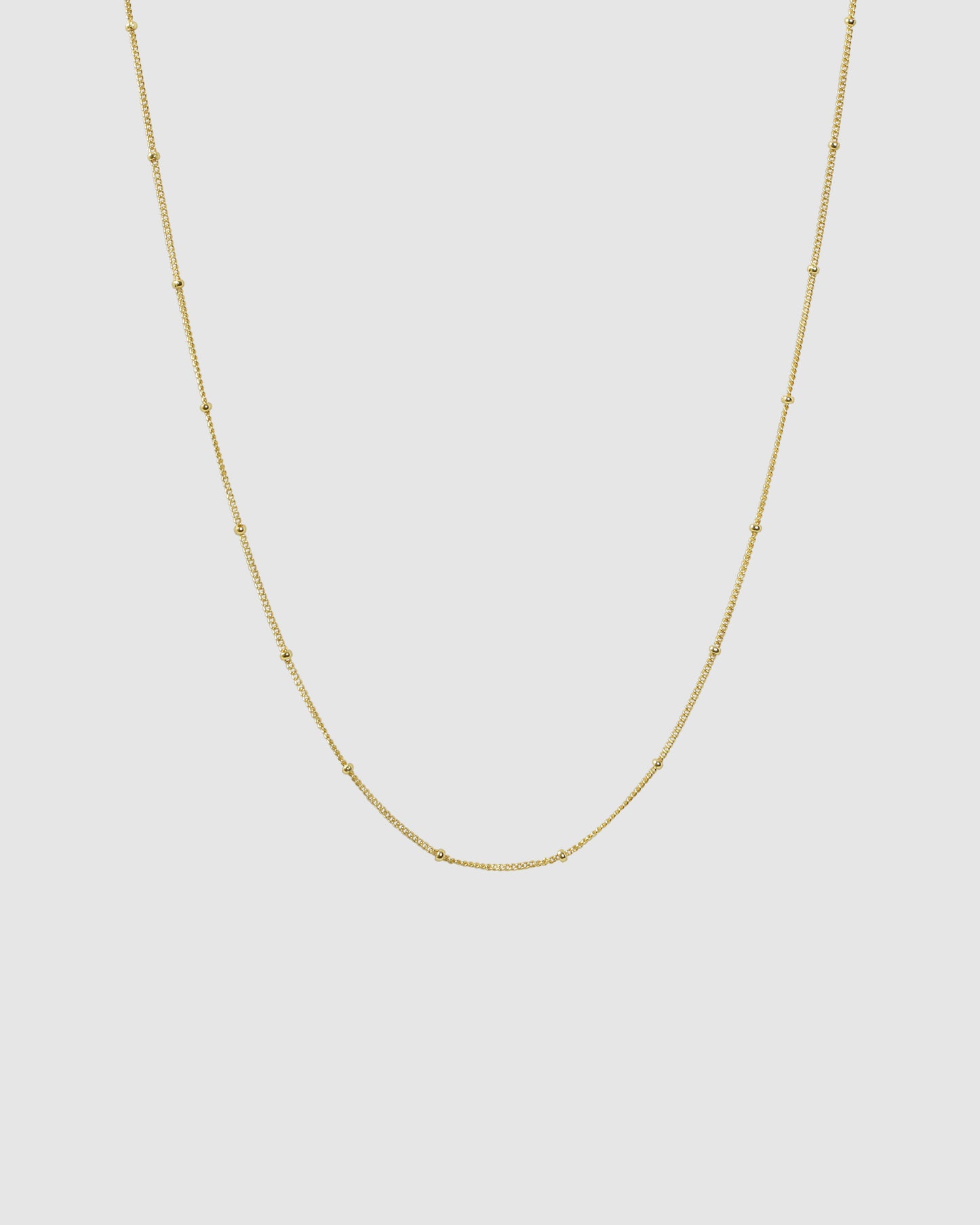Gold Dot Chain necklace on a plain background.