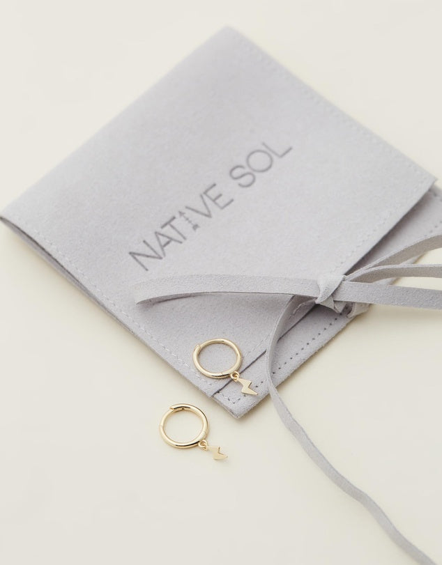 Lightning Bolt Huggies - Gold flat lay on grey jewellery pouch
