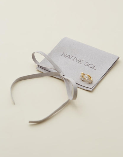 Natasha Diamond Huggies sitting on branded jewellery pouch