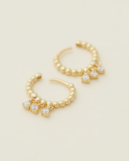 Sage Huggies - Gold close up of earrings on beige background