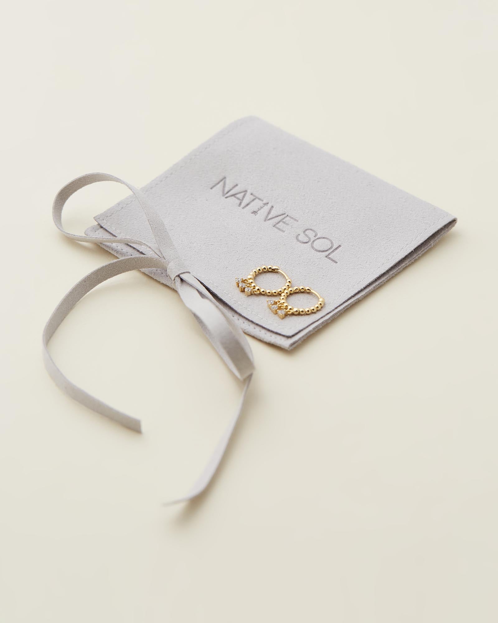Sage Huggies - Gold close up flat lay on branded jewellery pouch